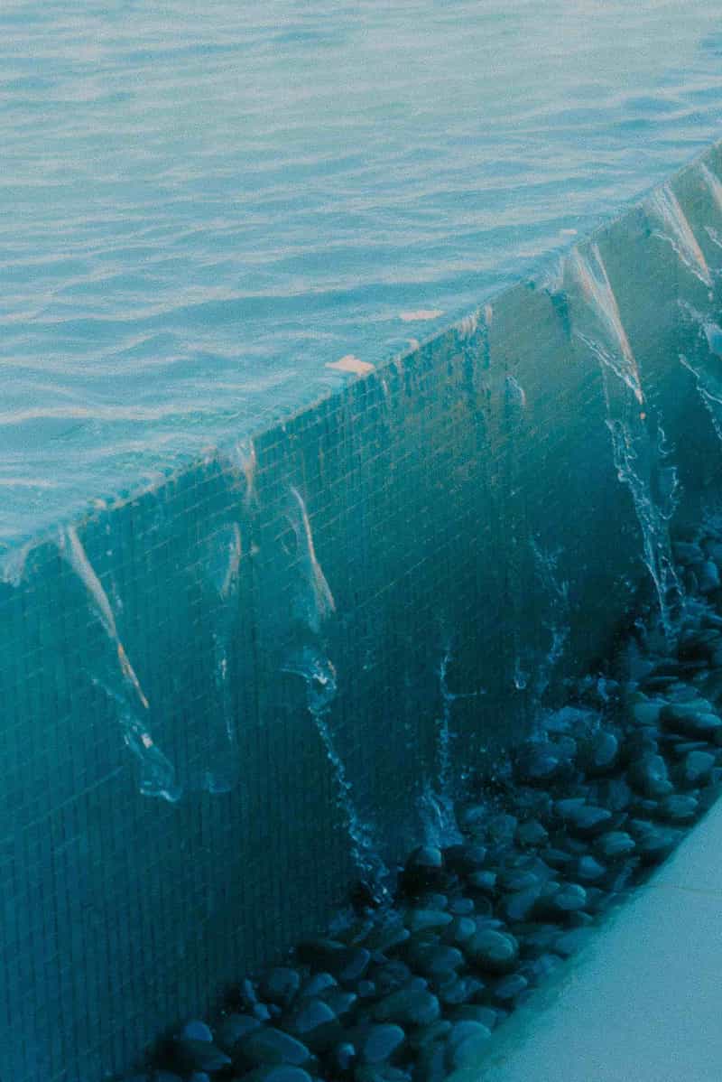 Overflowing pool edge with turquoise water and stone base in Playa del Coco, Costa Rica